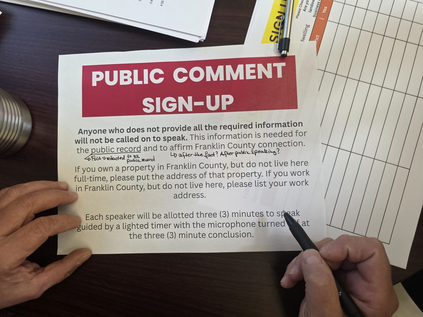 The county's public comment sign-up sheet, stating that each speaker will be allotted three minutes. Handwritten notes question the public record language.